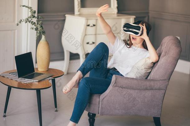 年幼的女人调节她VirtualReality虚拟现实戴在头上的耳机或听筒和微笑的在期间在家