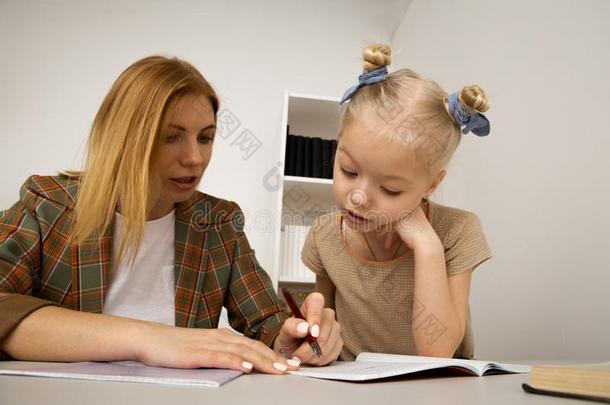 小的小孩学习和母亲在指已提到的人书桌在家.