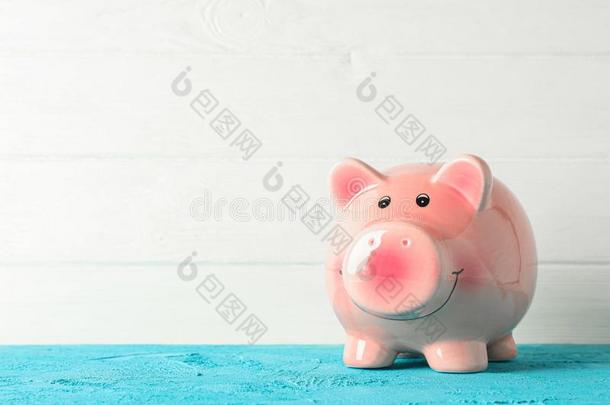 幸福的小猪银行向颜色表反对白色的木制的背景,