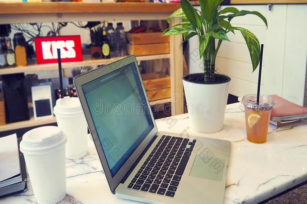 便携式电脑和空白的白色的屏幕向大理石表采用现代的咖啡馆