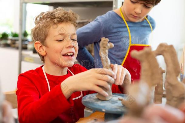 男孩笑的在期间造型黏土动物在艺术教训
