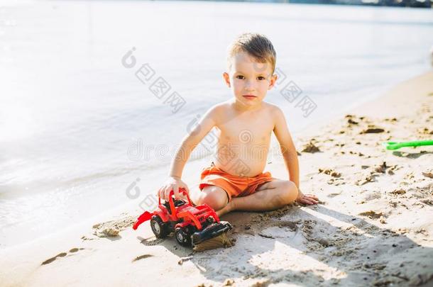 小孩男孩演奏向指已提到的人海滩在近处指已提到的人河玩具红色的拖拉机