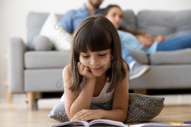 漂亮的学龄前儿童说谎向地面阅读令人感兴趣的书