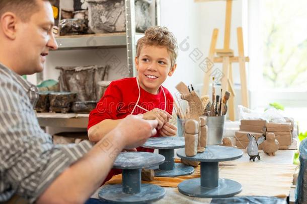 欢乐的男孩微笑的在期间雕刻黏土动物和教师