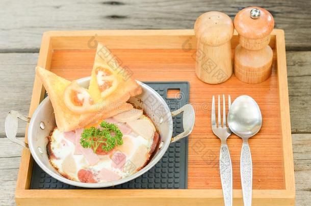 平底锅-喝醉了的鸡蛋和配品向木制的背景.早餐食物