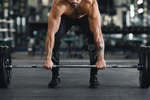 肌肉的家伙举起重的杠铃从健身房地面
