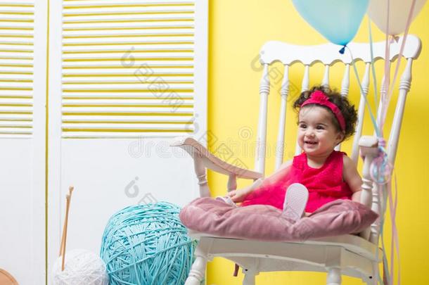 幸福的微笑的甜的婴儿女孩一次向扶手椅和生日