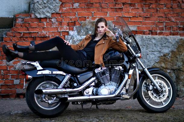 肖像关于美丽的年幼的女人使摆姿势和摩托车
