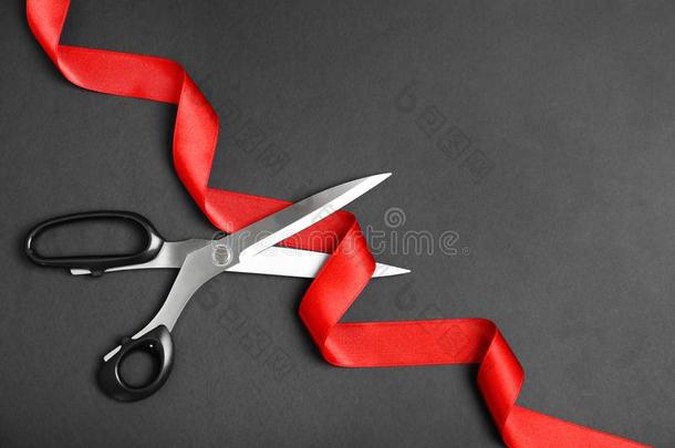 时髦的剪刀和红色的带向黑的背景,平的放置.英语字母表的第3个字母