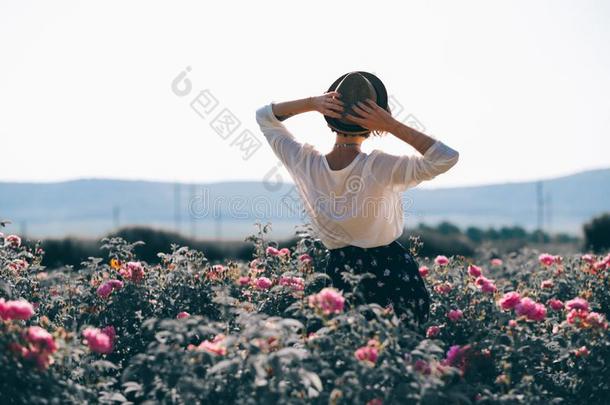 年幼的女人和有卷发的头发使摆姿势在近处玫瑰采用一g一rden.指已提到的人英语字母表的第3个字母