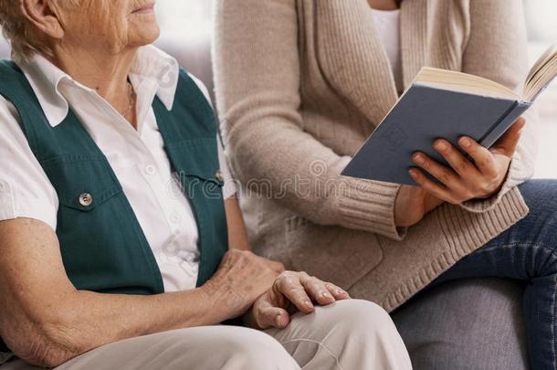 较高的女人和给予帮助的志愿者在护理家阅读书