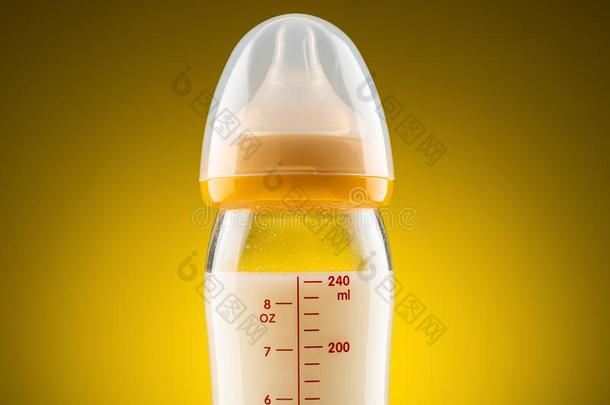 从背后照亮的玻璃婴儿瓶子和变成粉的奶特写镜头向地位较高的爸