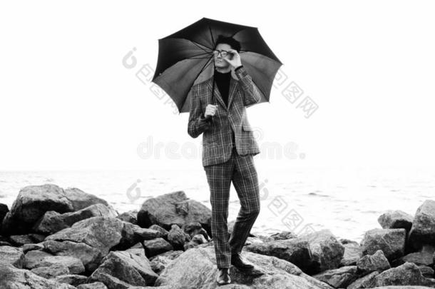 流行的年幼的男人和雨伞起立在近处指已提到的人海
