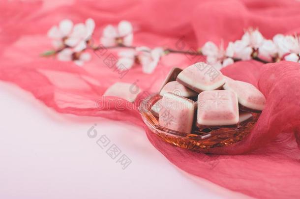 粉红色的巧克力条和白色的花向粉红色的和红色的背景.