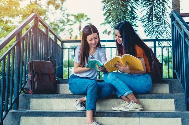 两个亚洲人美好女儿阅读和当家庭教师书为最后的考试