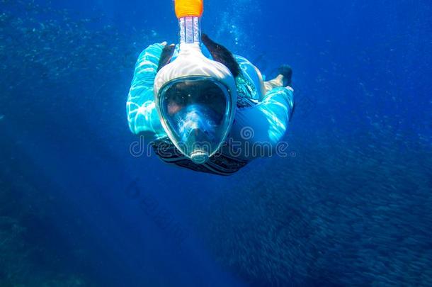 女人游泳采用蓝色海.女孩snorkel采用g采用满的-面容面具.英文字母表的第19个字母