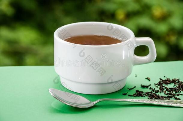 杯子关于茶水和勺向一绿色的b一ckground.关-在上面.
