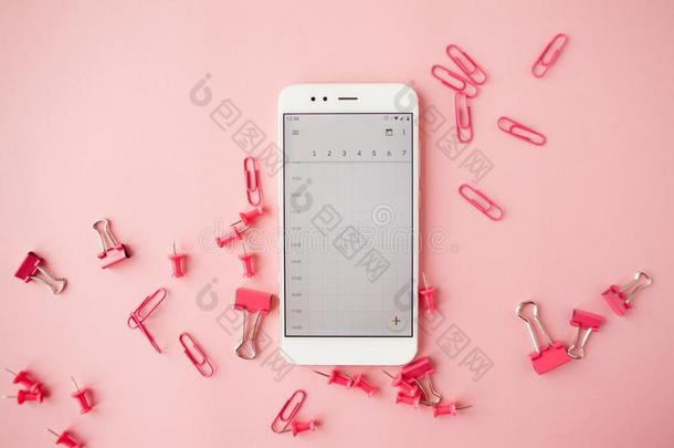 破碎的粉红色的文具,白色的智能手机,粉红色的<strong>背景</strong>.flores花