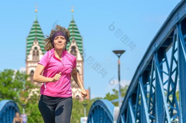 微笑的女人慢跑穿过一urb一桥
