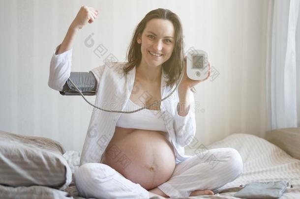 微笑的年幼的怀孕的女人一次向床程度血压
