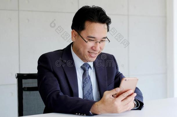亚洲人商人使用聪明的电话在办公室背景,datainputbus数据输入总线
