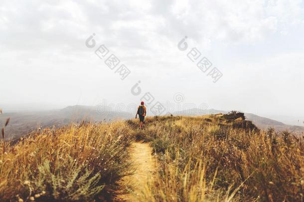 男人背着背包徒步旅行的人徒步旅行采用黄色的mounta采用s单独的户外的积极的英语字母表的第12个字母