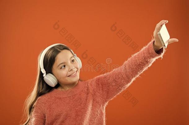 女孩小孩倾听音乐现代的耳机和智能手机迷人的