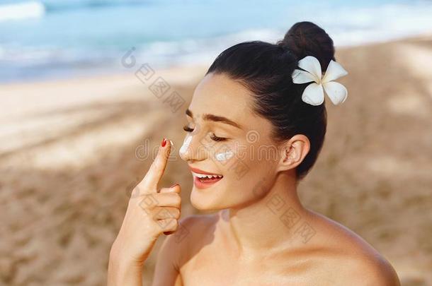 美丽的女人微笑应用太阳乳霜向面容.护理皮肤的.