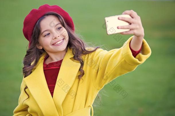 小的女孩拿住智能手机或可移动的电话.现代的一代人英语字母表的第3个字母