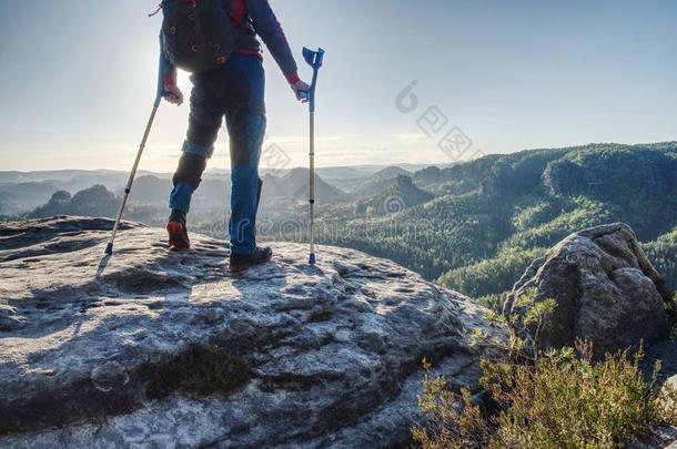 损害强的男人起立和拐杖向山顶点