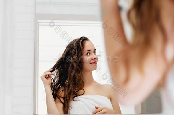 头发和身体关心.女人令人同情的湿的头发和微笑的在期间int.看