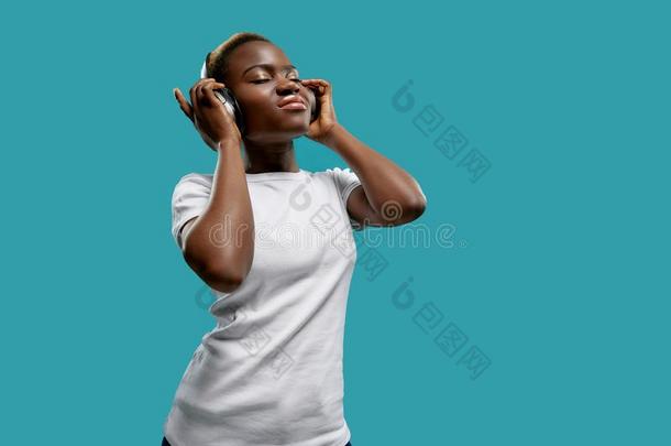 非洲式发型女人收听的音乐和耳机和关闭着的眼睛.