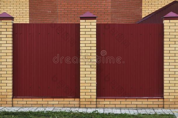 栅栏使关于砖和装饰的金属.红色的栅栏和黄色的
