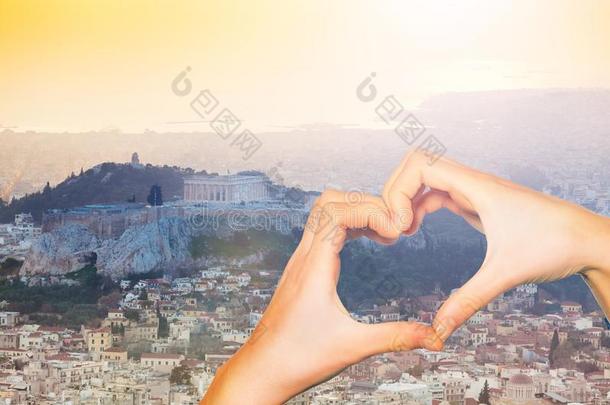 手拿住红色的心越过日落采用雅典,希腊