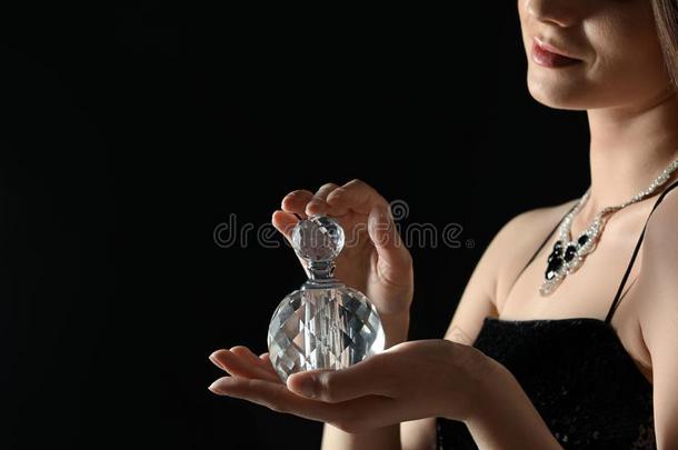 年幼的女人和瓶子关于香水向黑的背景,特写镜头
