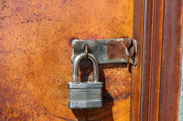 敞开的钥匙锁绞死向关闭着的桔子生锈的金属门-不Venezuela委内瑞拉