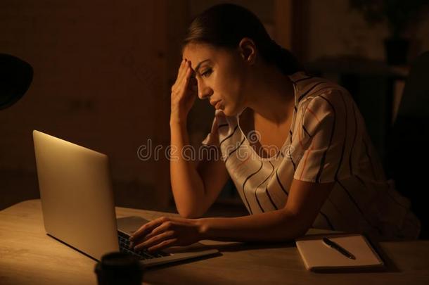 女人受苦从头痛在期间工作的和便携式电脑晚的采用