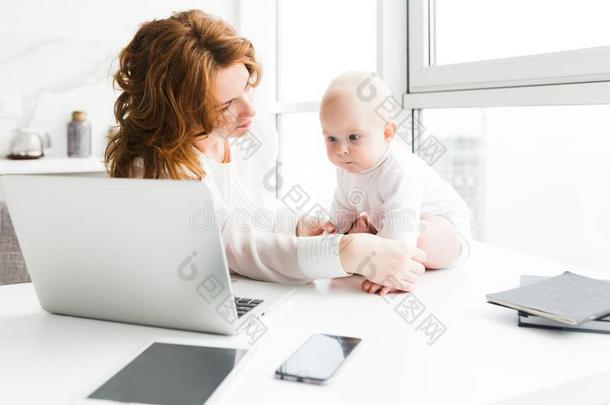 年幼的漂亮的母亲一次和便携式电脑向表和快乐地厕所