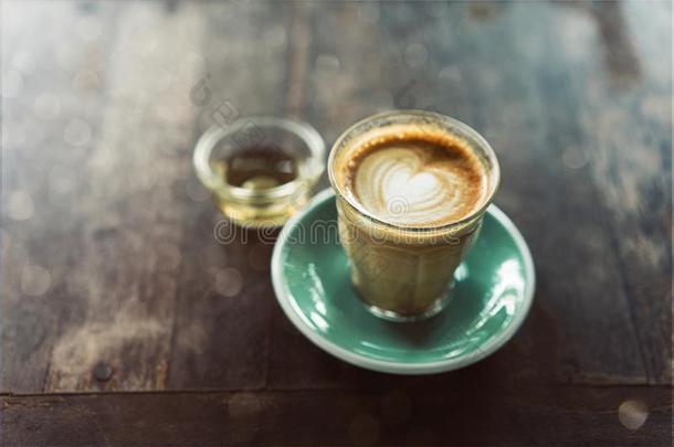 咖啡豆杯子拿铁咖啡艺术和绿色的茶杯托向木材背景