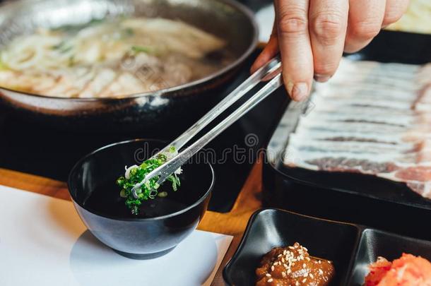 男人收聚切碎青葱采用油漆调味汁和钳为dipp采用