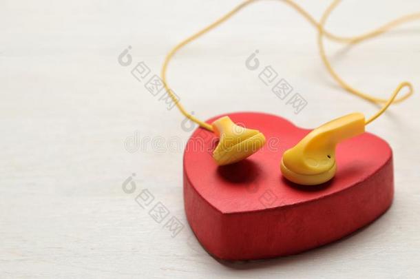 小的黄色的耳机和红色的装饰的心向一白色的木材