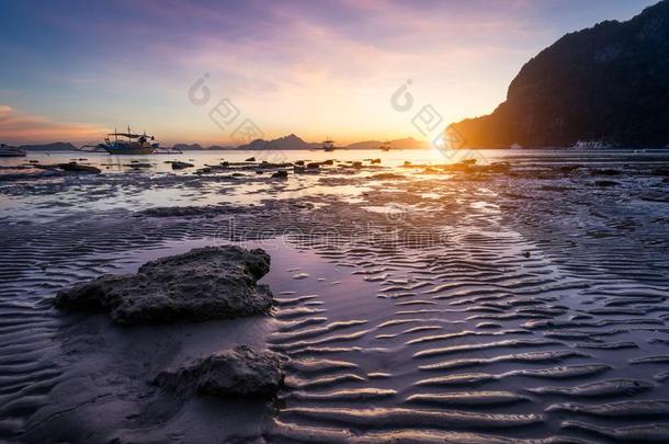 热带的海滩采用退时间低的潮汐向日落.海边淤泥地和太阳