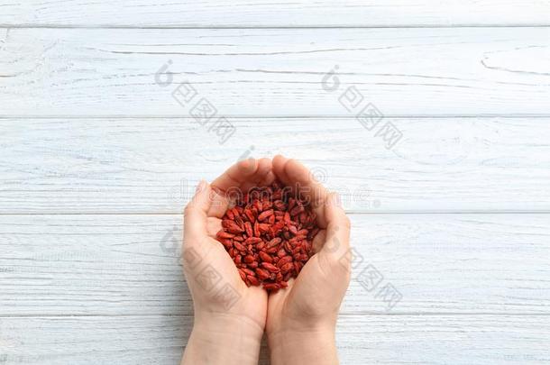 女人佃户租种的土地红色的干燥的枸杞浆果向白色的木制的背景