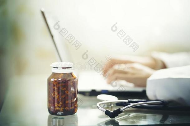 医生使用便携式电脑和瓶子关于医学的药物