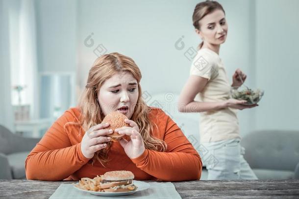 困恼的留长发的女孩出行向吃汉堡包