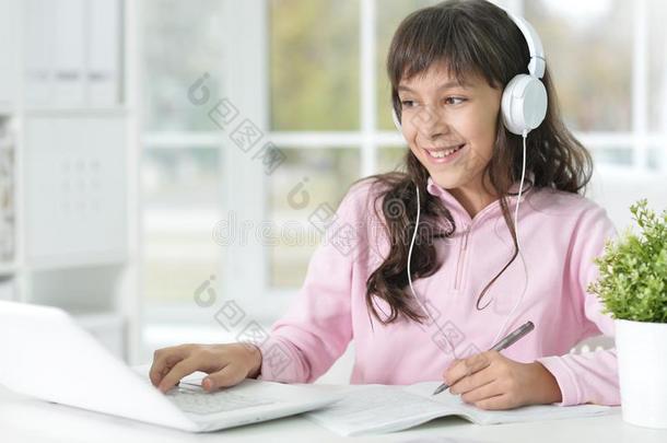 肖像关于小的女孩使用便携式电脑在期间学习在书桌