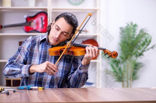 年幼的英俊的修理工纠正小提琴