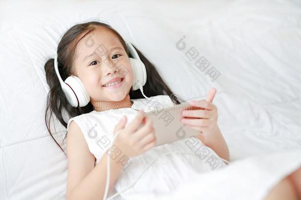 幸福的小的亚洲人女孩使用耳机倾听音乐在旁边聪<strong>明人</strong>