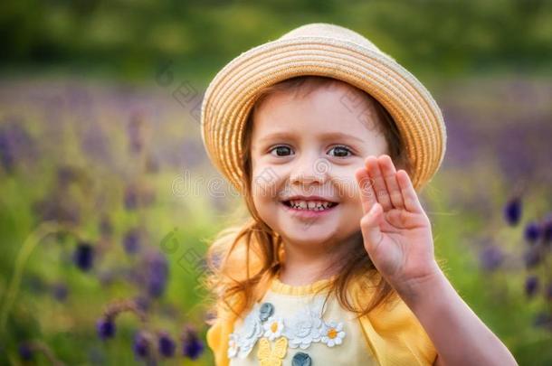 漂亮的微笑的婴儿女孩采用米黄色帽子在户外采用绿色的田.希腊字母的第22字