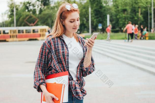 有魅力的红发的人微笑的女孩学生和电话采用她手